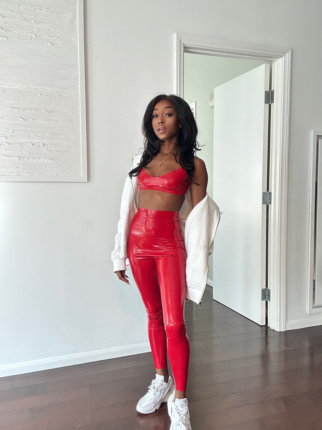 Jheanelle in a stylish two-piece red latex outfit with a hoodie, exuding a confident and sporty allure
